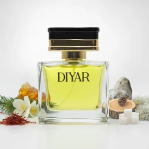 Genzey Diyar perfume bottle surrounded by saffron strands, white blossoms, amber resin, pinecones, wooden slices, sugar cubes, and green foliage
